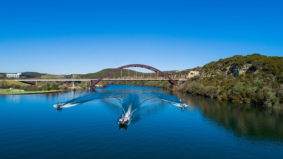 Wake boat, surf boat, and luxury tritoon at the 360 bridge on Lake Austin